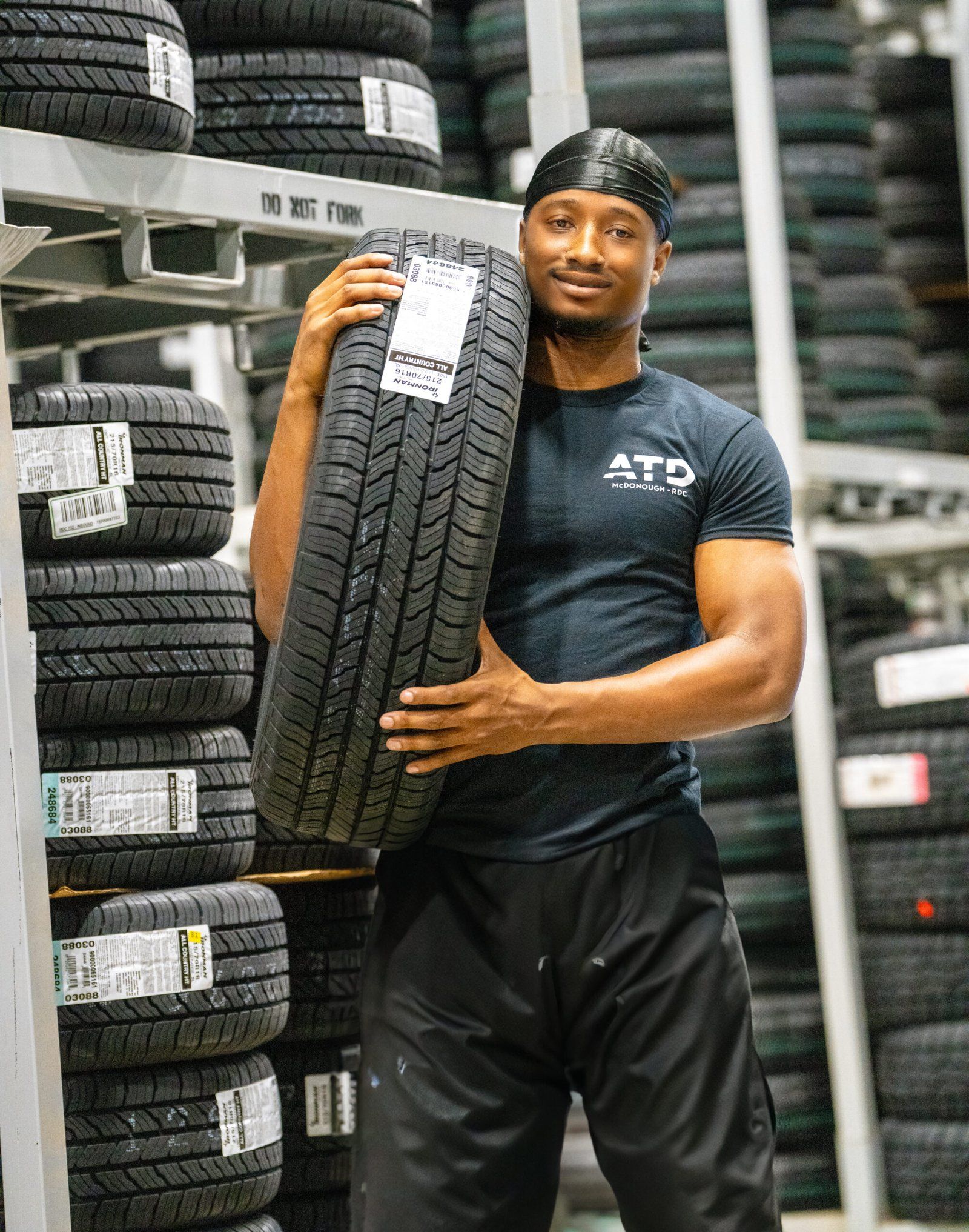 Associate carrying a tire beside tall racking