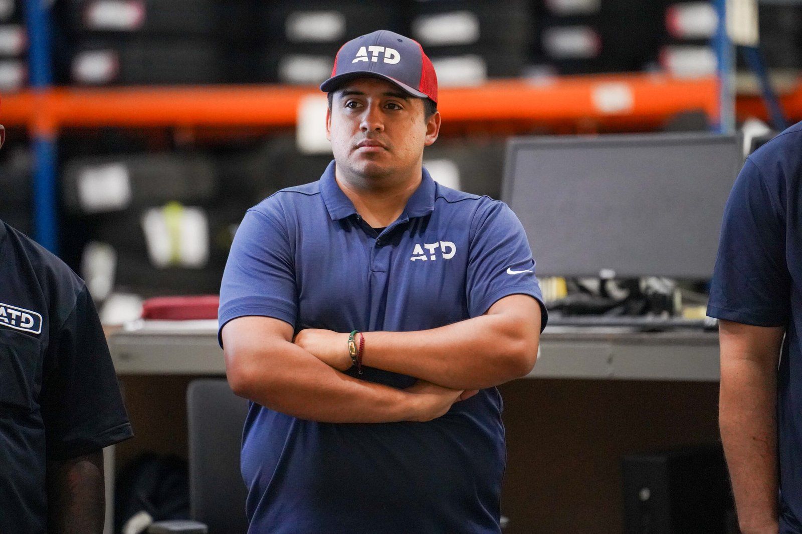 Associate with arms crossed in a branded polo